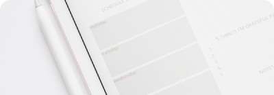 A white schedule planner with a pen